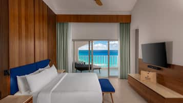 Habitación de hotel con cama, televisión, minibar y balcón con vista al océano.