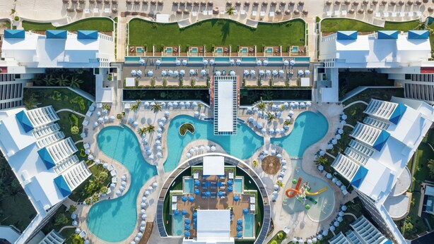 An aerial view of a resort with multiple swimming pools, a beach, and a central building. - Hilton Cancun Mar Caribe All-Inclusive Resort (Cancun)
