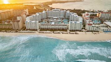 A resort with multiple buildings, a beachfront, and a large pool area.