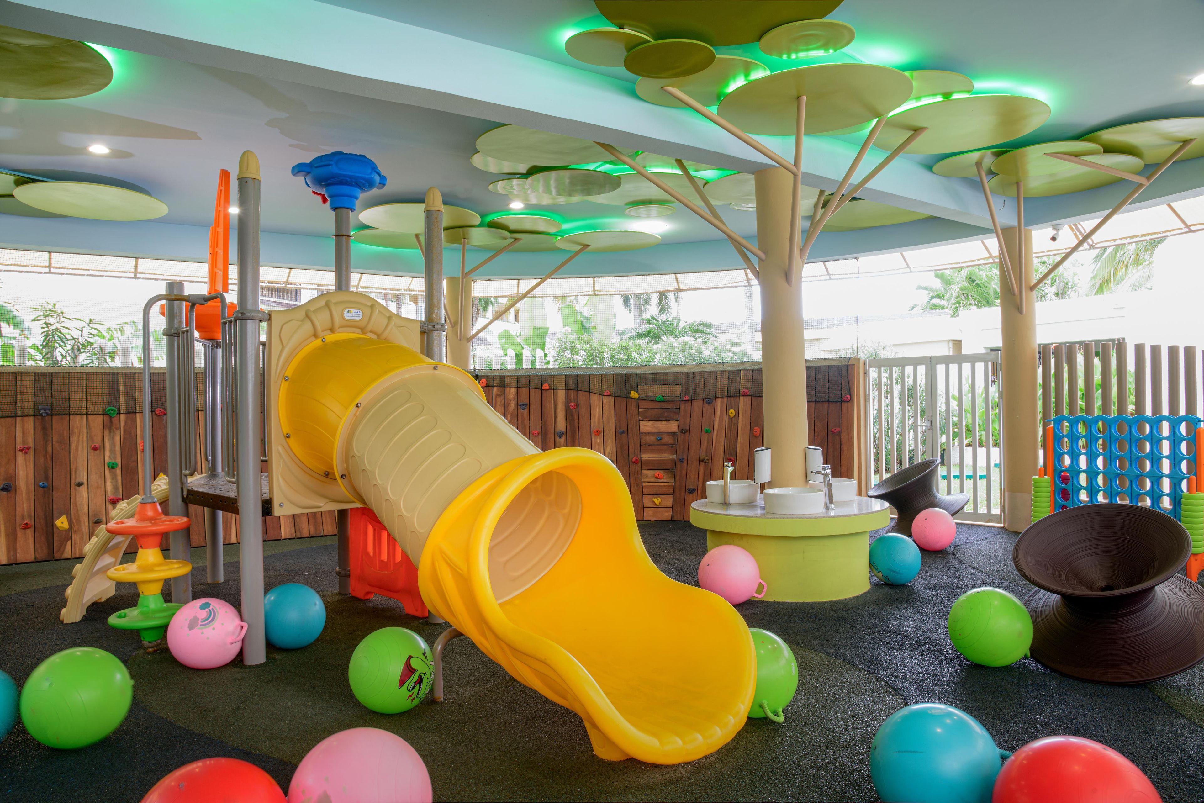 A children's play area with a slide, climbing wall, and various play equipment.