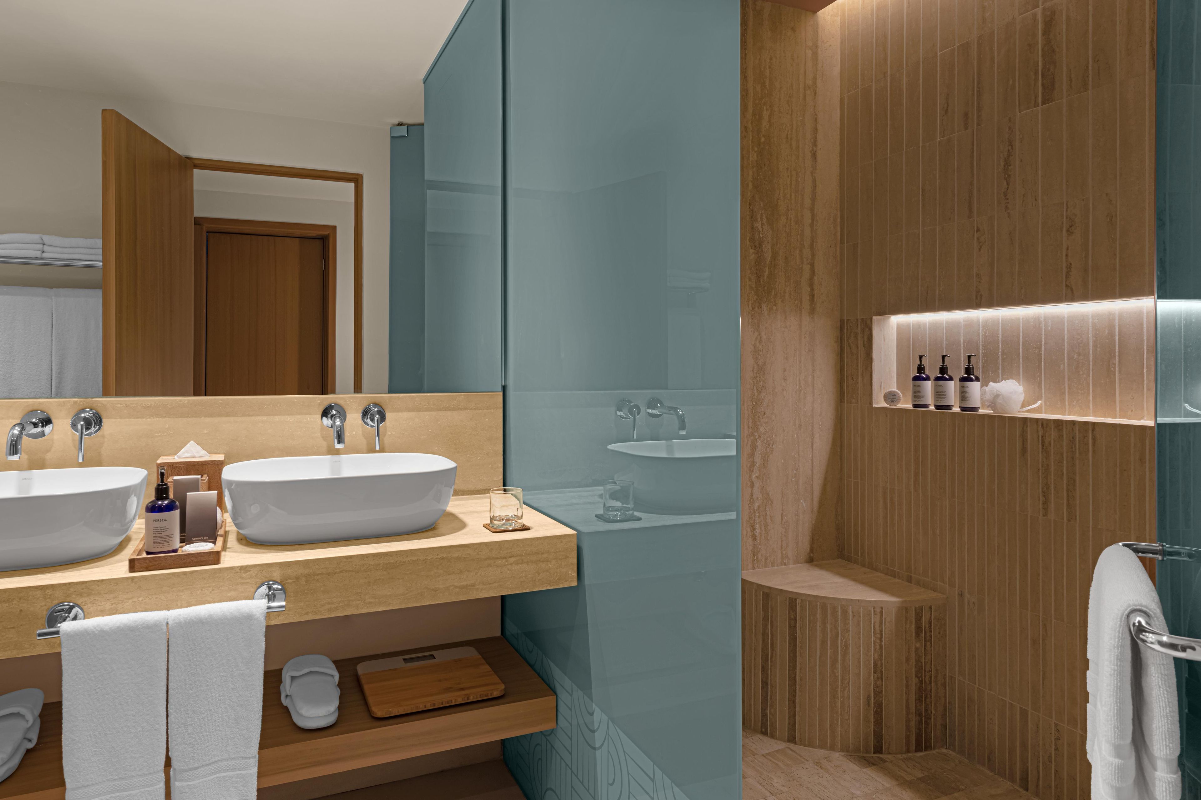 Ein modernes Badezimmer mit zwei Waschbecken, einem Spiegel und einem Waschtisch mit Pflegeprodukten.