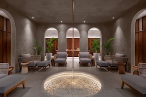 A modern lobby with a central water feature, seating area, and wooden accents.