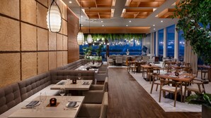 A modern restaurant with a cozy seating area, wooden ceiling, and large windows offering a view of the cityscape. - Hilton Cancun Mar Caribe All-Inclusive Resort (Cancun)