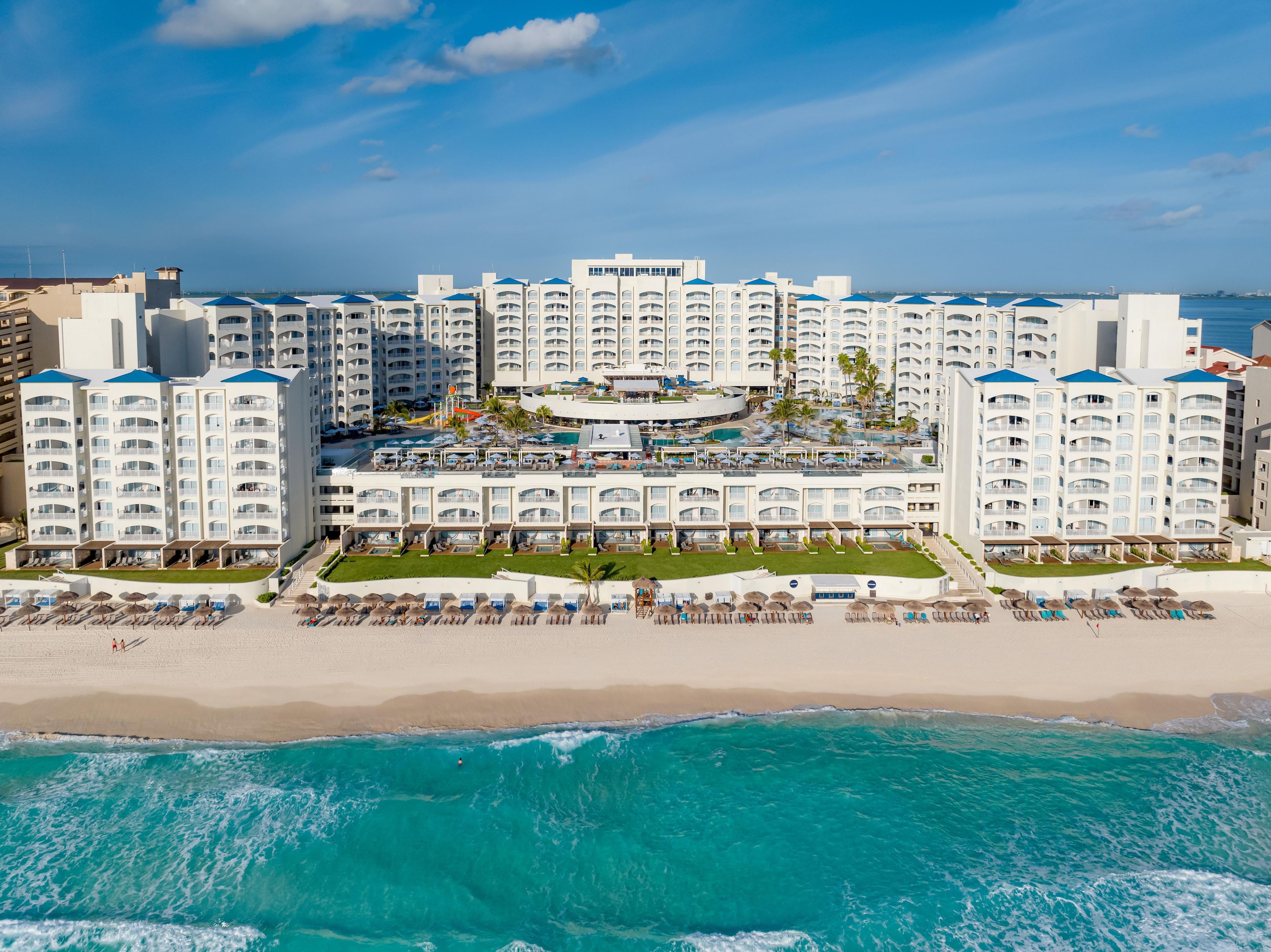 A beachfront hotel with multiple balconies, a pool area, and a beach.