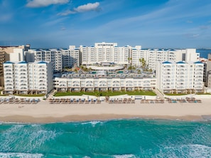 A beachfront hotel with multiple balconies, a pool area, and a beach. - Hilton Cancun Mar Caribe All-Inclusive Resort (Cancun)