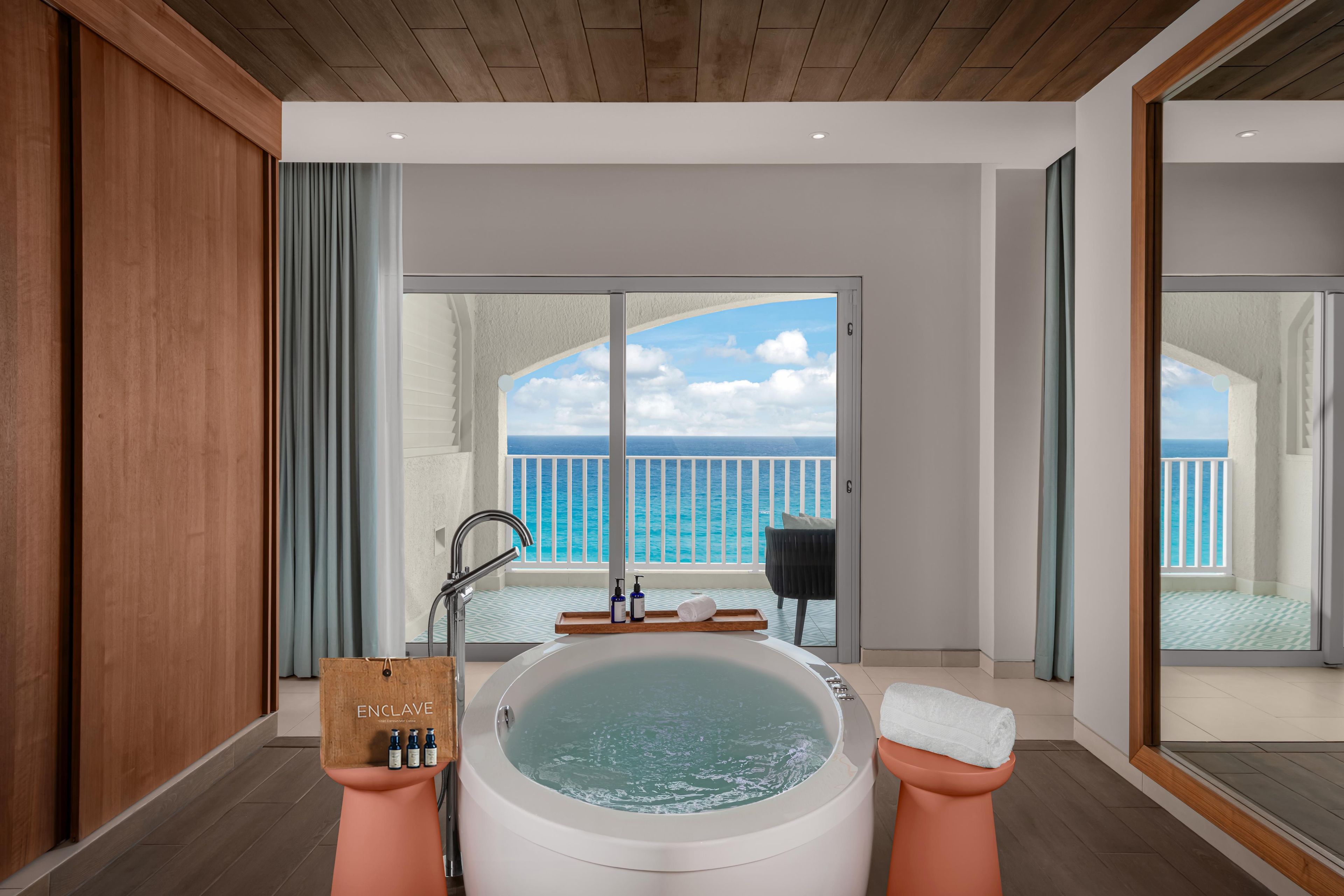 Un baño moderno con bañera, ducha y vistas al océano.