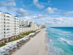 A beachfront hotel with multiple balconies, a sandy beach, and ocean views.