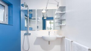 A modern bathroom with a white sink, a shower, and a mirror above the sink. - Calcebianca (Ostuni)