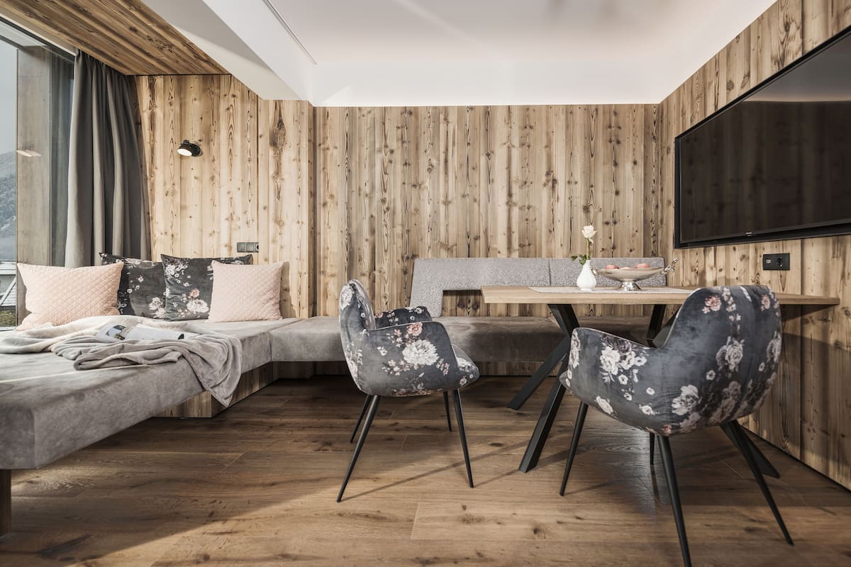 Une chambre moderne avec un mur en bois, un lit, un canapé, une table à manger avec des chaises et un téléviseur.