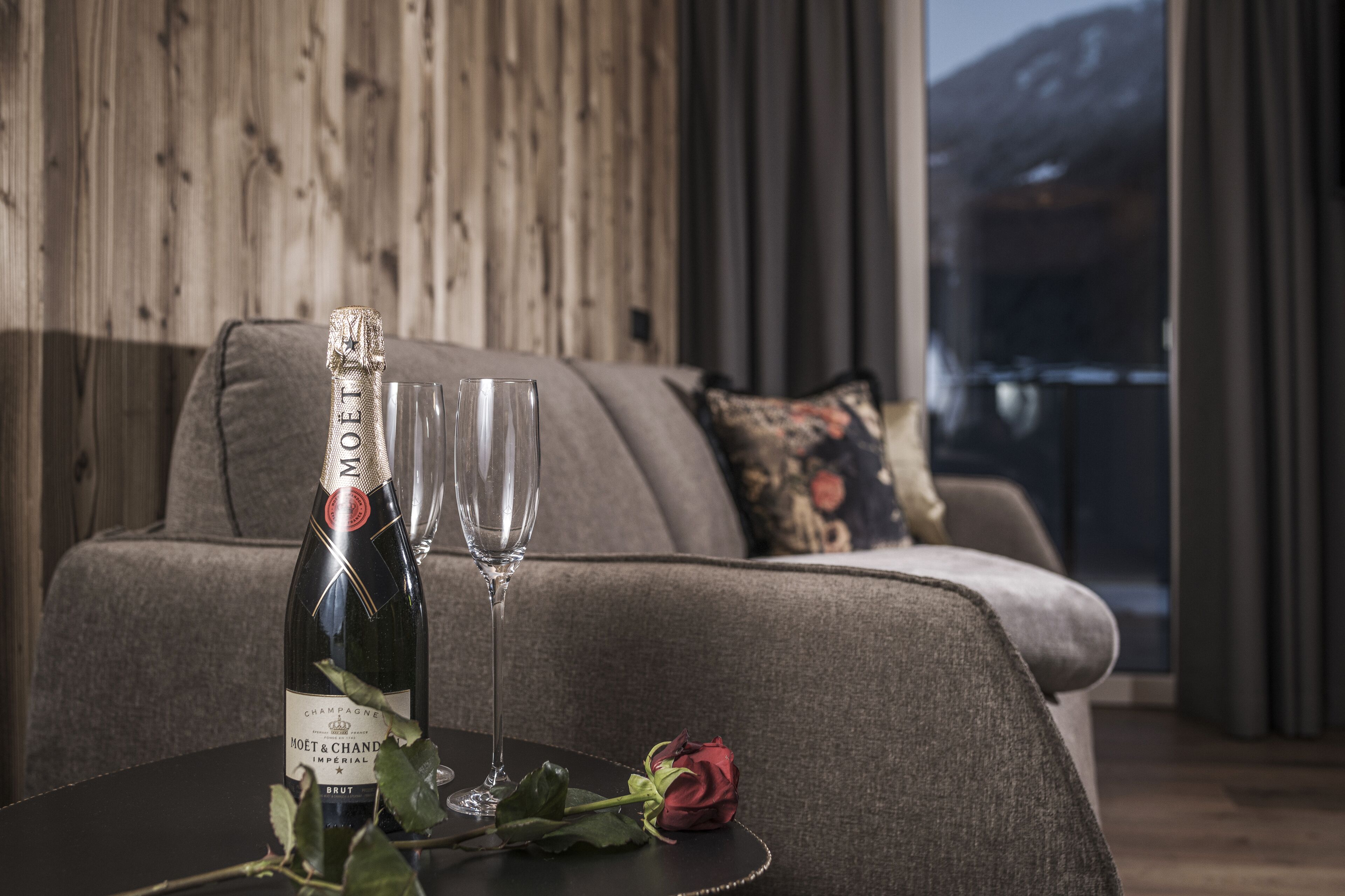 A bottle of Moet & Chandon champagne on a table with a glass and a rose.