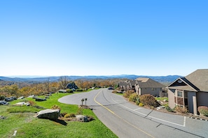 A residential street with houses, a winding road, and a clear view of distant mountains.