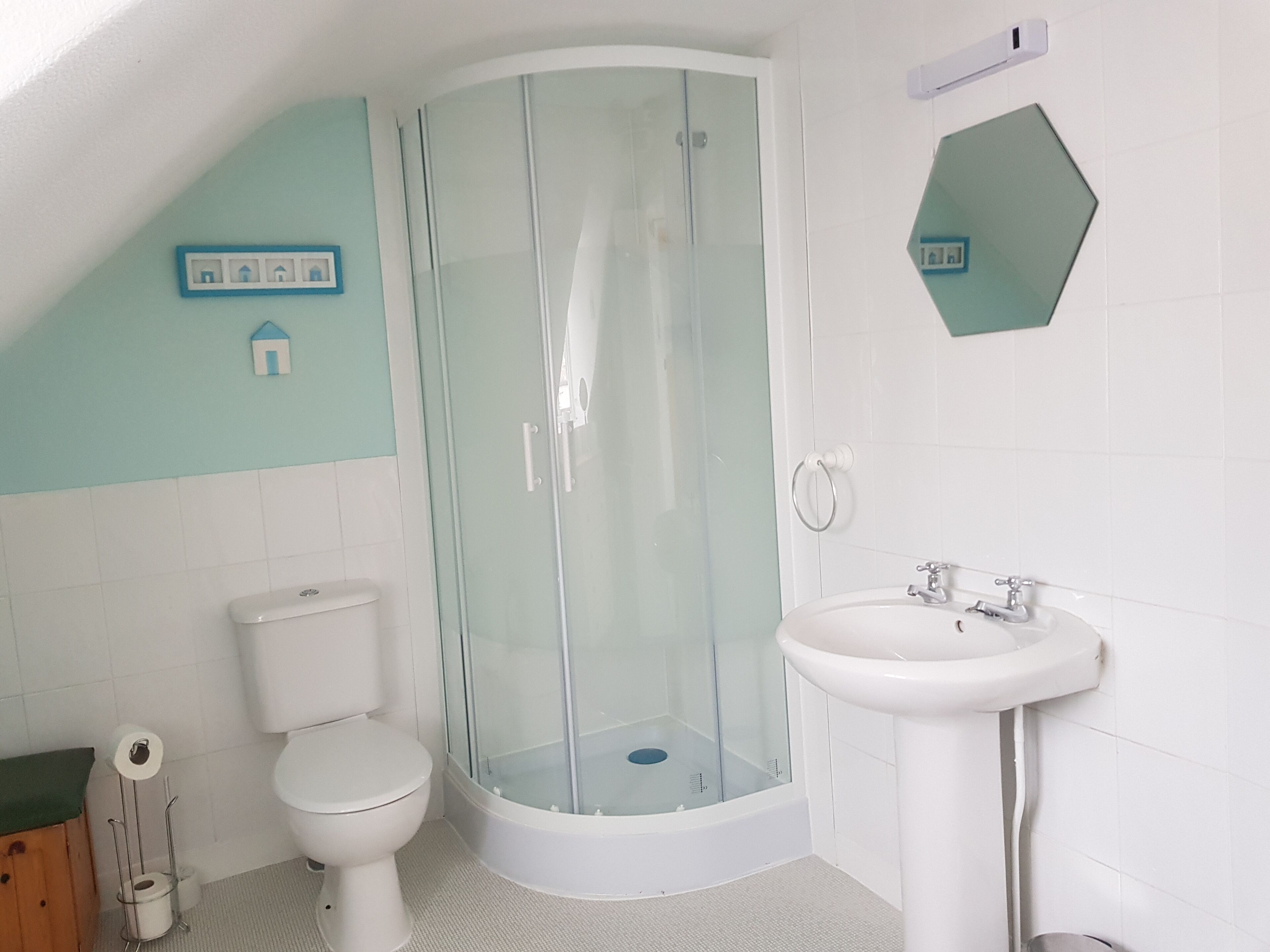 A bathroom with a glass-enclosed shower, a toilet, and a sink.