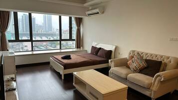 Una habitación de hotel moderna con una cama, un sofá, un escritorio y un ventanal que ofrece vistas a la ciudad.