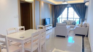 A modern living room with a white dining table, white chairs, a sofa set, and a television. - R&F Princess Cove at R&F Mall (Johor Bahru)