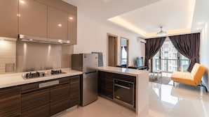 A modern kitchen with a built-in oven, a refrigerator, and a stove. There is a dining area with a table and chairs, and a large window with curtains. - R&F Princess Cove at R&F Mall (Johor Bahru)