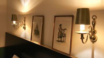 A hotel room with a bed, a headboard, and wall-mounted sconces with lamps.