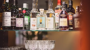Una barra con varias botellas de licores, vasos y utensilios de bar.