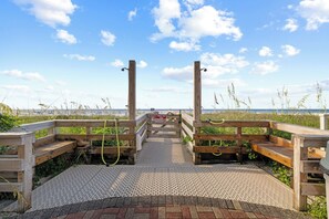 A wooden boardwalk leading to a beach with a 'No Swimming' sign.