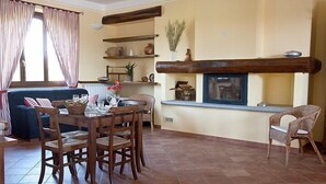 Un salon chaleureux comprenant un coin repas, une cheminée et un canapé.