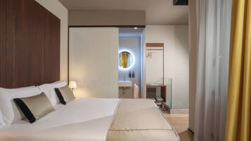 A hotel room with a large bed, a bedside table, a mirror, a bathroom with a sink, and a door with a curtain.