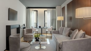 A modern living room with a sofa, armchairs, a coffee table, and a dining area with a table and chairs. - Speronari Suites (Milan)
