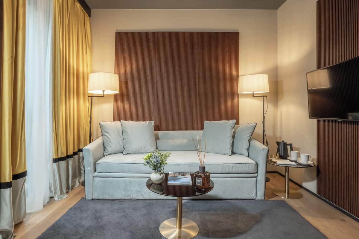 A modern living room with a sofa, two floor lamps, a coffee table, and a TV.