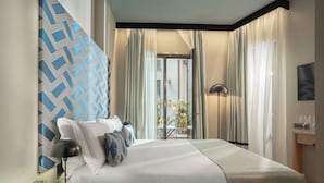 A hotel room with a bed, a nightstand, a lamp, a window with curtains, and a view of the outside. - Speronari Suites (Milan)