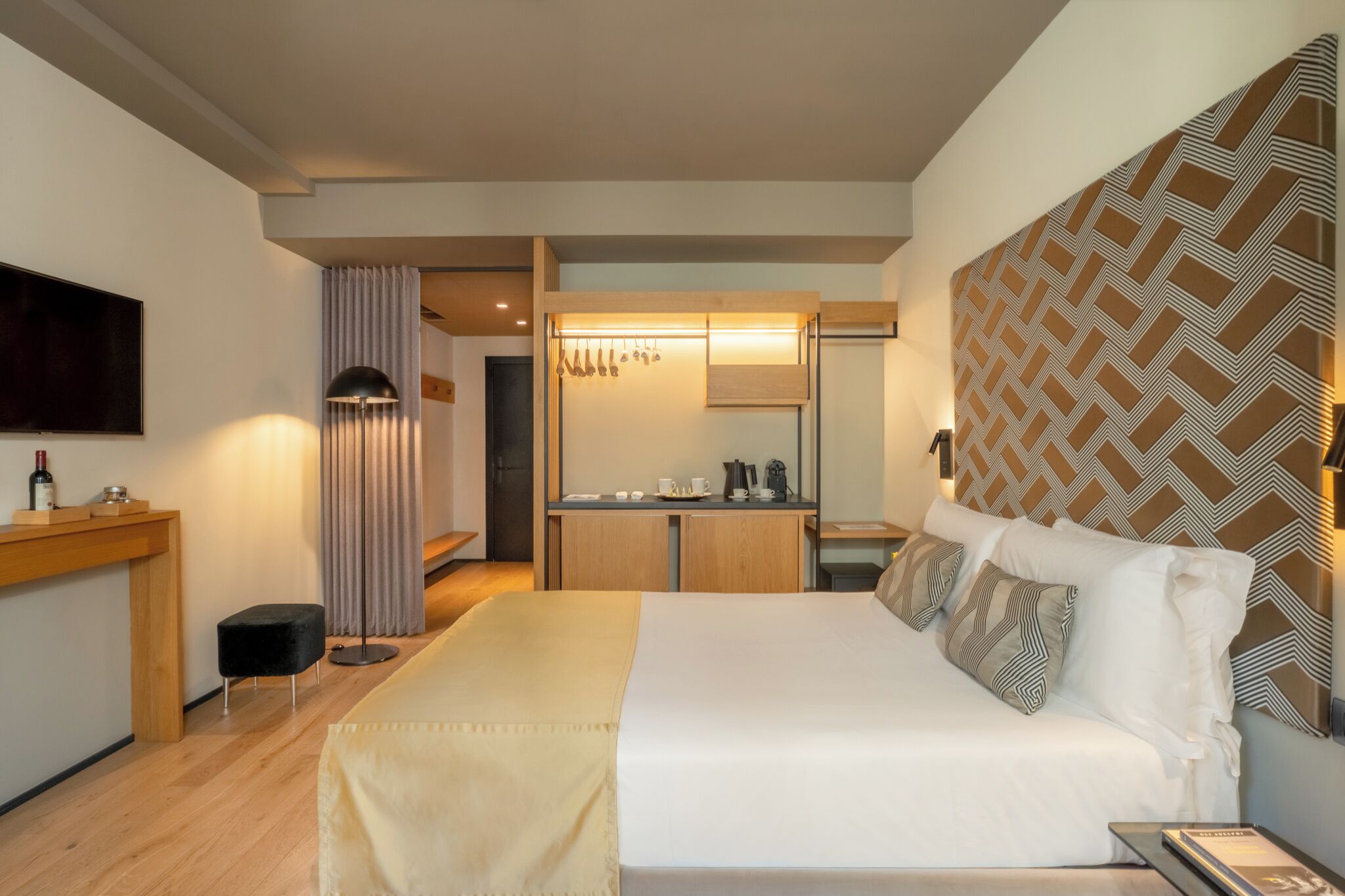 Et moderne hotelværelse med seng, skrivebord, spejl og fjernsyn.