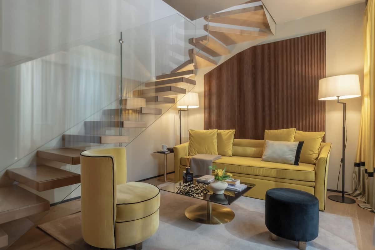 A modern living room with a staircase, a sofa, a coffee table, and a lamp.