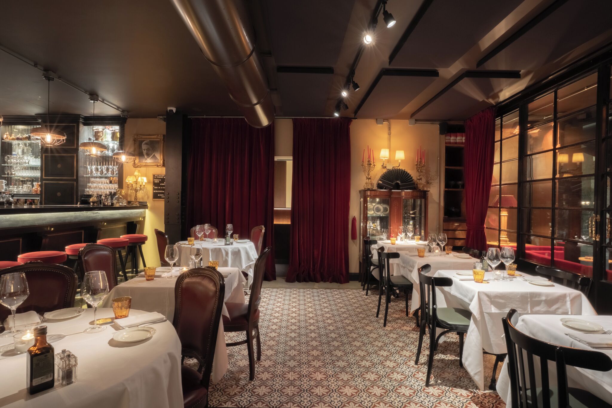 Ein Restaurant mit gedeckten Tischen, einer Bar mit Flaschenregalen und einem gemusterten Boden.