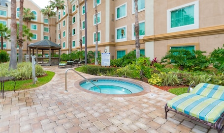 A hotel courtyard with a swimming pool, lounge chairs, and a gazebo.