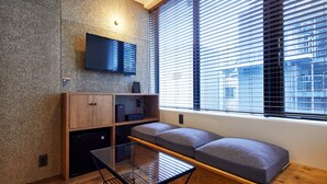 Ein modernes Zimmer mit einer eingebauten Bank, einem Glastisch und einem Flachbildfernseher an einer strukturierten Wand.