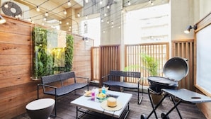 A wooden deck with outdoor seating, a grill, and a wall with vertical gardens. - mizuka Daimyo 6 - unmanned hotel - (Fukuoka)
