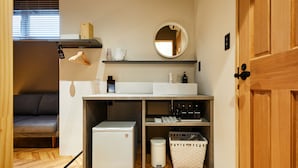 A compact kitchenette with a refrigerator, sink, and storage shelves. - mizuka Daimyo 6 - unmanned hotel - (Fukuoka)