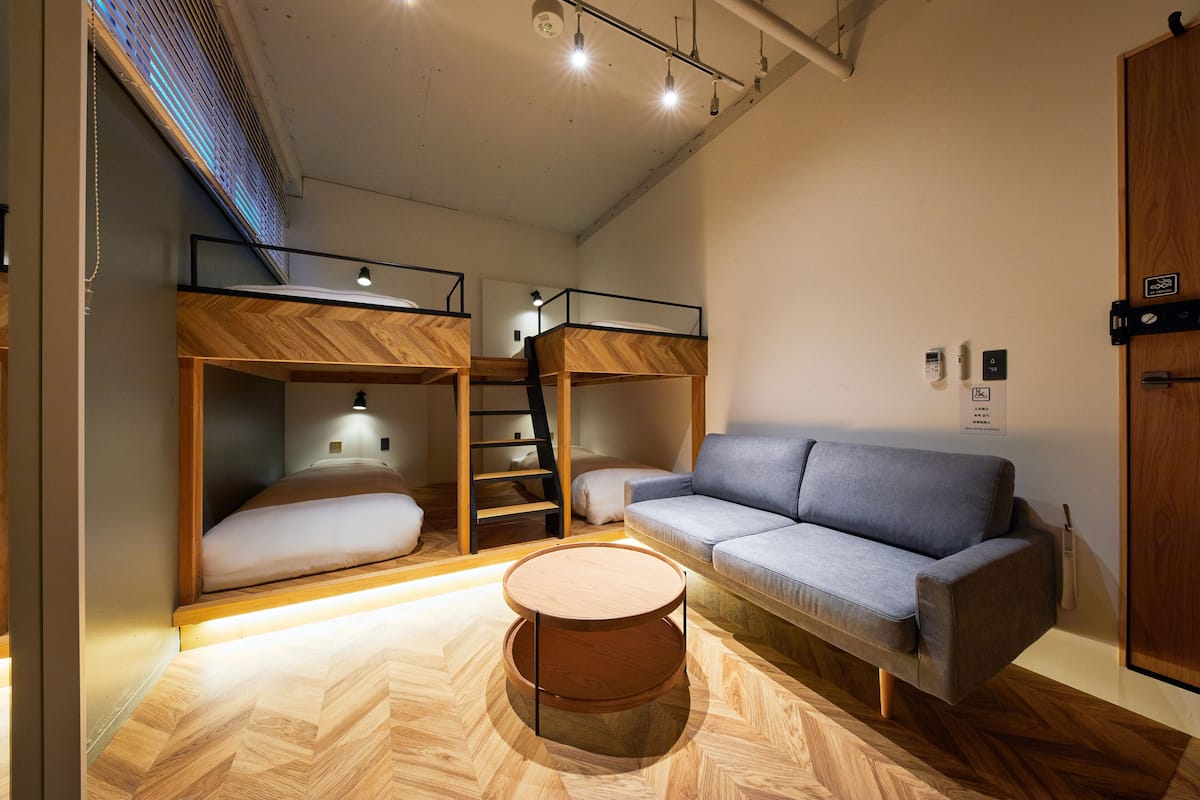 Une chambre moderne et compacte, équipée de lits superposés, d’un canapé et d’une table basse ronde.