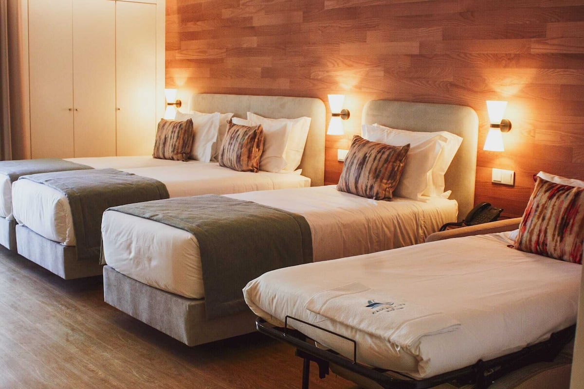 Habitación de hotel con dos camas individuales, cada una con cabecero y lámparas de noche.
