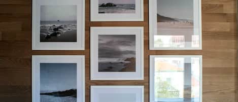 Six framed photographs of coastal scenes arranged on a wooden wall.