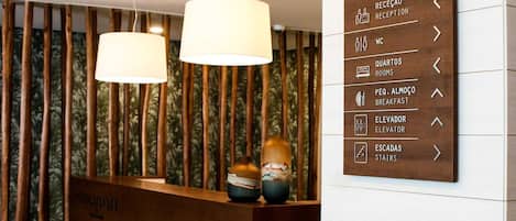 A reception desk with a wooden panel wall and a directional sign.