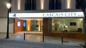 The exterior of Cascais City Beach hotel with a modern facade, a visible reception area, and a logo with a sailboat. - Cascais City Beach Hotel (Cascais)