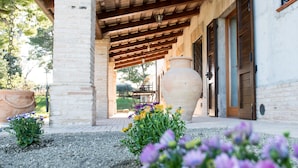 Un espace extérieur abrité, doté d’un pilier en briques, de grands pots en terre cuite et de portes en bois.