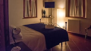 Une chambre à coucher avec un lit, une lampe de chevet et une petite table sur laquelle est posée une plante.