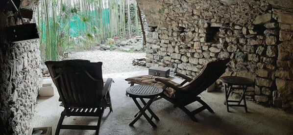 A stone-walled outdoor seating area with two lounge chairs and a small table. - Le Mas de la Filoselle (Saint-Martin-de-Valgalgues)