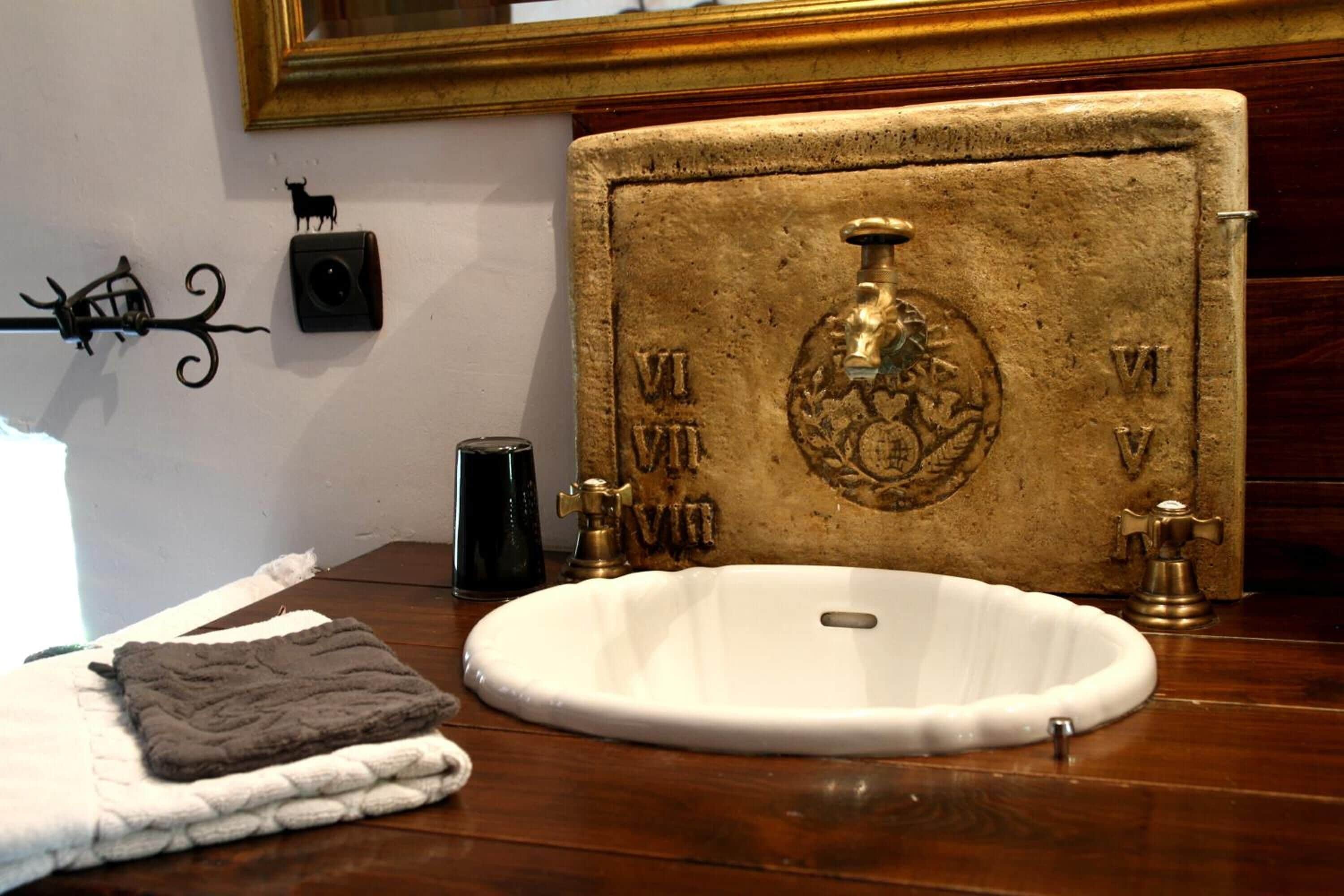 Un baño con un lavamanos antiguo, una toalla y un adorno de pared.