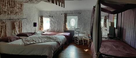 A room with two beds, a chair, a small table, and a window with curtains.