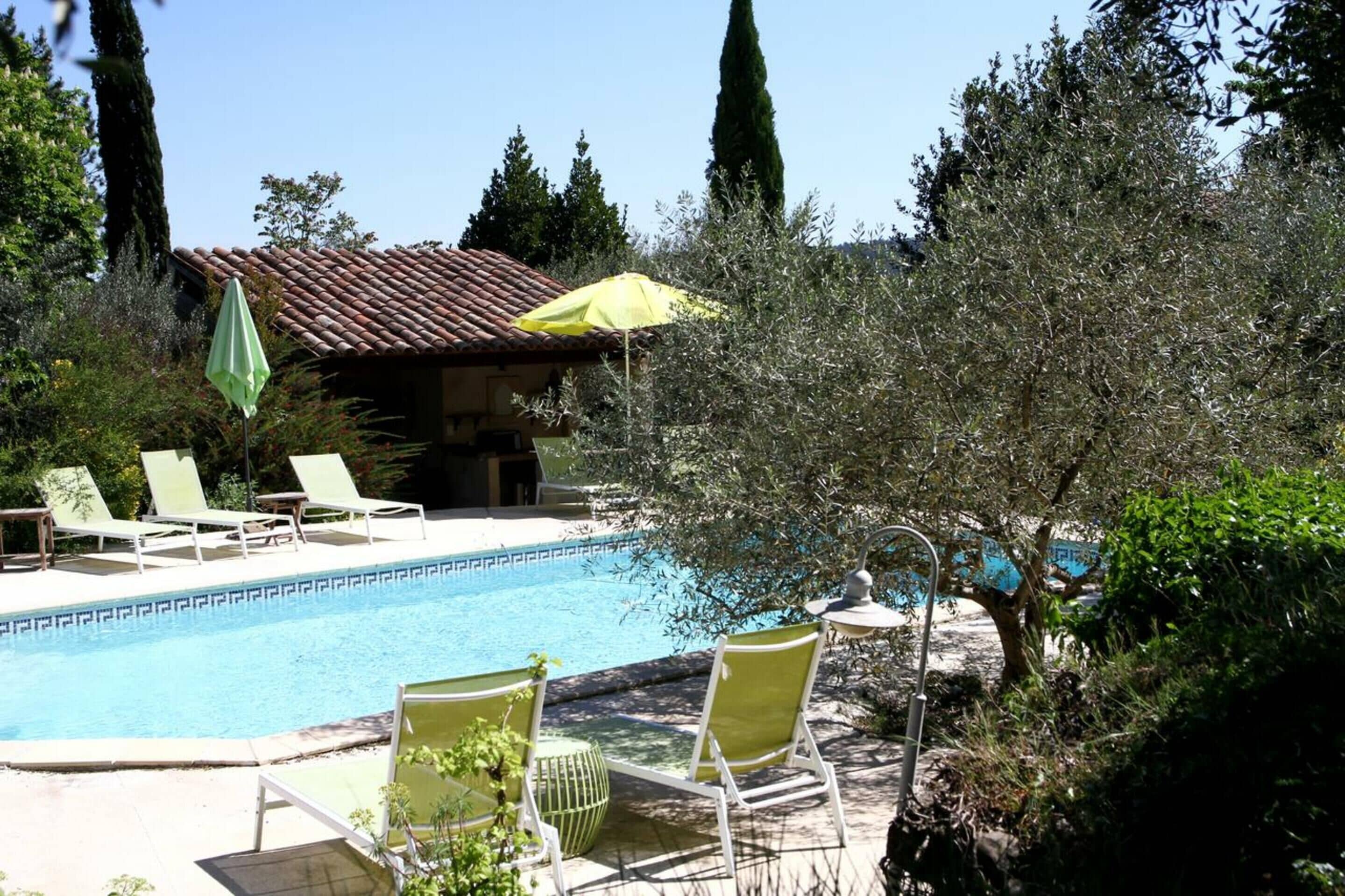 A pool area with lounge chairs and a building with a tiled roof.