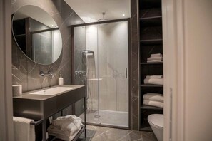 A modern bathroom with a large mirror, a sink, a shower enclosure, and a toilet. - Be Mate Via Tivoli (Milan)