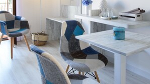 A modern living room with a flat-screen TV, a sofa, a dining table, and a floor lamp. - Les Suites des Tout le Monde (Sorrento)