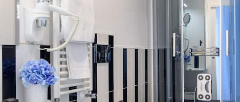 Un baño moderno con un tocador blanco, un inodoro, una cabina de ducha y un espejo redondo.