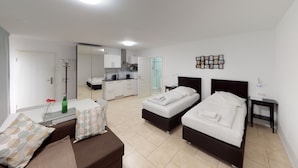 Una habitación de hotel moderna con dos camas, una kitchenette, un baño y un comedor.
