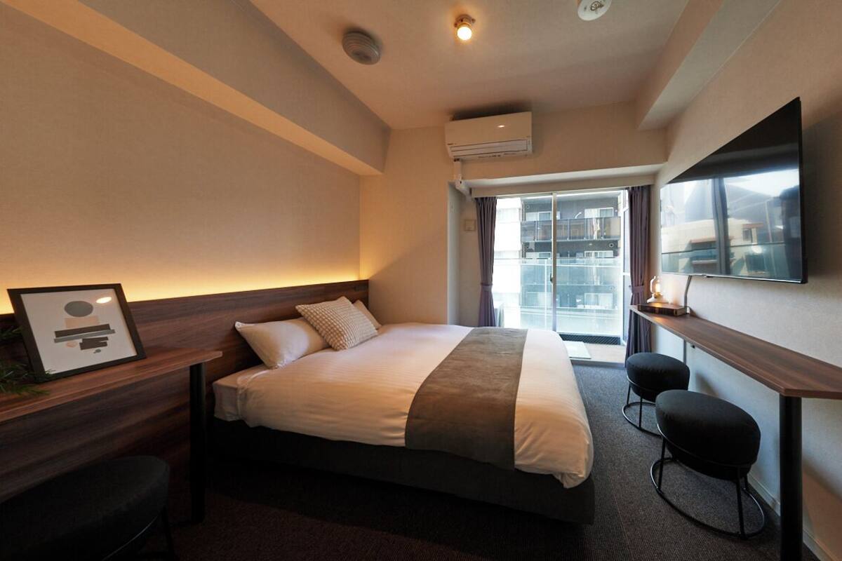 Une chambre d’hôtel équipée d’un lit, d’un bureau, d’une chaise, d’un climatiseur et d’une télévision.